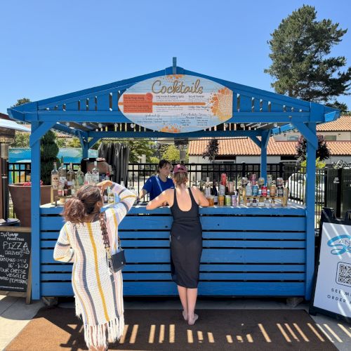 Image shows two people standing by a blue wooden booth labeled 