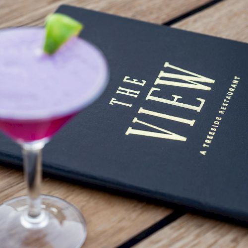 A purple cocktail with a lime wedge and a menu titled 